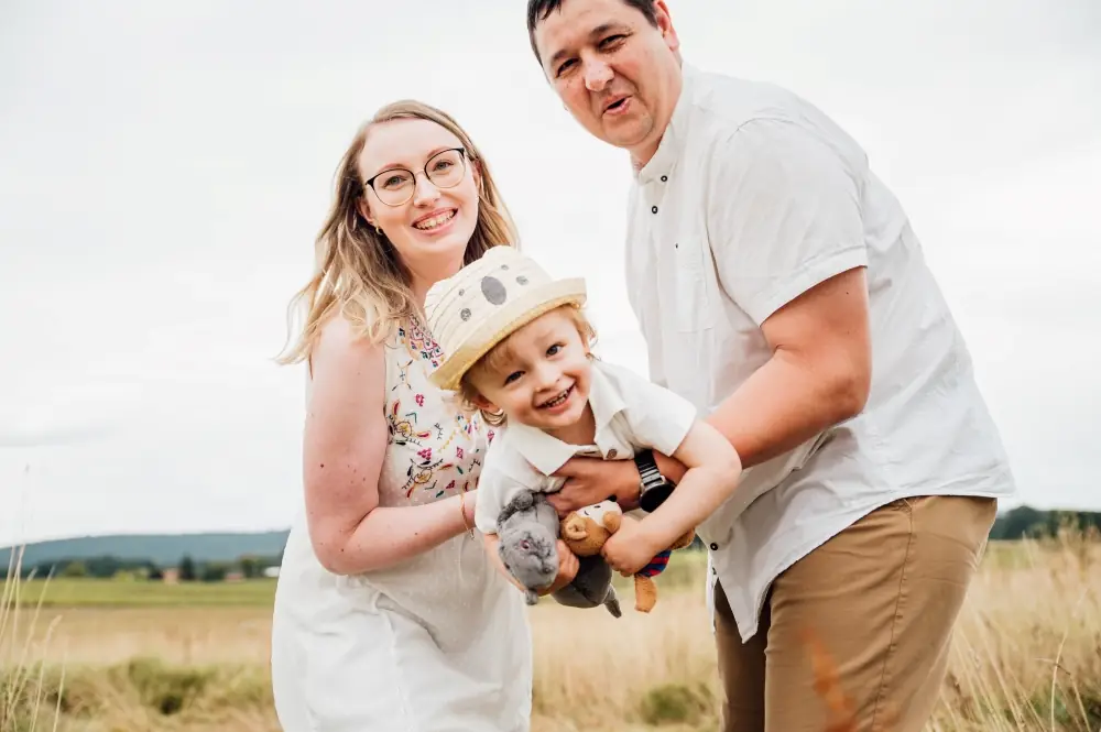 Lachende Familie mit Kleinkind auf einem Feld